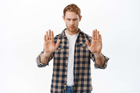 Serious and confident redhead man telling to stop, showing no prohibition gesture, taboo on...