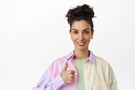 Modern brunette woman with pierced nose, combed hair, show thumbs up and say yes, recommend...