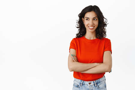 Smiling jewish brunette girl, cross arms on chest confident and relaxed, looking left at logo with...