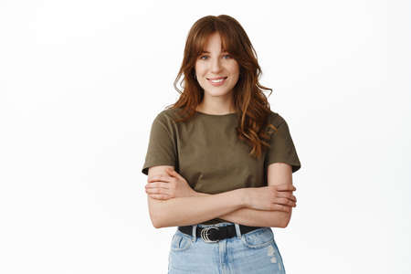 Portrait of confident girl with crossed arms, look determined and ready, smiling with white teeth,...