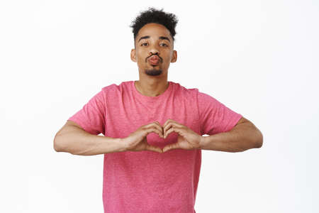 Lovely and silly african american guy, boyfriend kissing and showing love heart gesture, I love you...