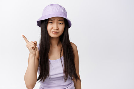 Young asian woman give warning, shaking finger and looking disappointed, scolding someone, standing over white backgroundの写真素材