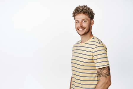 Handsome blond guy smiling happy at camera, looking motivated and hopeful, standing in confident...
