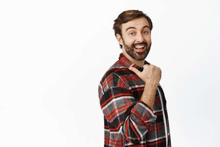 Enthusiastic smiling man pointing left, showing big promo offer, sale or discount in store, standing...