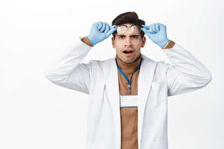 Shocked and confused doctor takes off glasses, frowning and staring frustrated, cant understand smth strange, looking with disbelief, white backgroundの写真素材