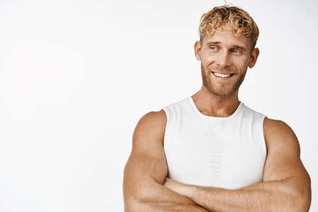 Sport and fitness. Handsome sportsman cross arms and smiles, standing in activewear against white backgroundの写真素材