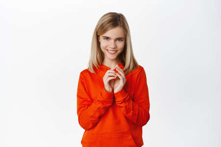 Image of cunning little girl, planning smth, scheming, steeple fingers and making smug face, standing against white backgroundの写真素材