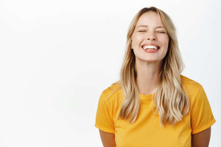 Happy people. Beautiful girl smiling and showing white perfect teeth, laughing carefree, standing in...