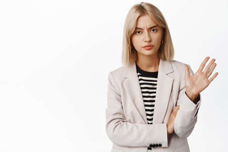 Enough, stop it. Reluctant lady boss, ceo businesswoman waving away and lookig disappointed, rejecting offer, refusing, standing over white backgroundの写真素材