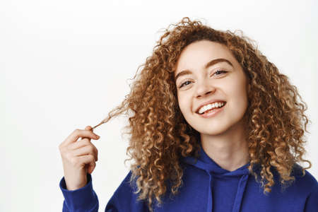 Skin care and cosmetology. Close up portrait of beautiful woman with curly hair, touches her healthy...