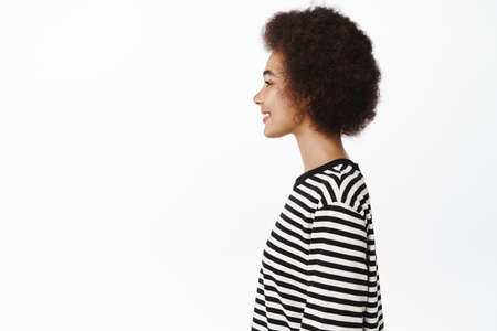 Profile portrait of young african woman with afro hair and casual clothes, healthy white smile,...