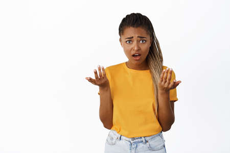 Frustrated Black woman shrugging, shaking hands clueless, cant understand, being confused, standing over white backgroundの写真素材