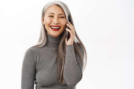 Portrait of beautiful and happy asian senior woman, middle aged lady talking on mobile phone,...