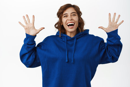 Winner, celebration. Portrait of enthusiastic young woman winning, triumphing, scream of joy and happiness, standing over white backgroundの写真素材