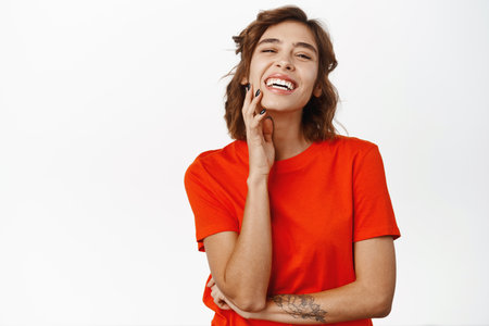 Women beauty and cosmetics. Beautiful brunette woman with white smile, natural clear skin without makeup, looking happy at camera, touching her face, white backgroundの写真素材