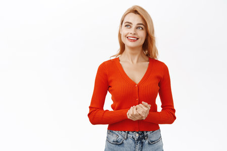 Portrait of young redhead woman holding hands together in professional pose, smiling friendly at customer or client, standing over white backgroundの写真素材
