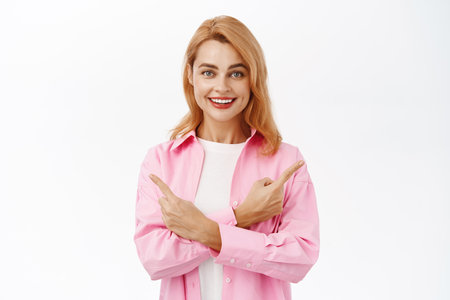 Portrait of cute smiling woman pointing sideways, showing two ways, left and right side banner, standing over white backgroundの写真素材