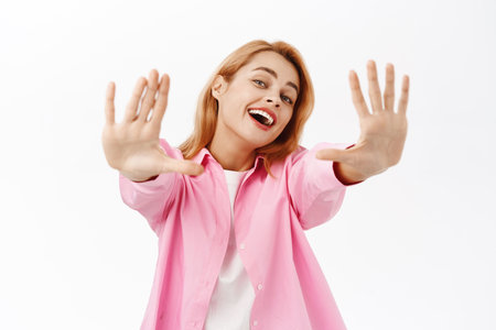 Beautiful girl extending her arms and smiling, standing over white studio backgroundの写真素材