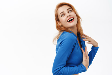Portrait of beautiful, stylish young woman looking confident and carefree, standing over white backgroundの写真素材