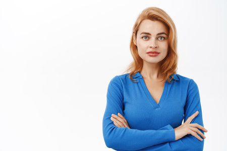 Close up of young professional woman, standing in power pose, cross arms on chest and looking confident, white studio backgroundの写真素材