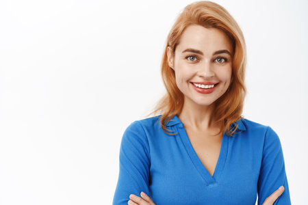 Professional young woman cross arms on chest, smiling, looking healthy and happy, posing in blue blouse against white studio backgroundの写真素材