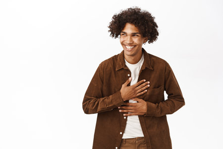 Portrait of happy hispanic young man, 20 years old, laughing and smiling, genuine happiness, standing over white backgroundの写真素材