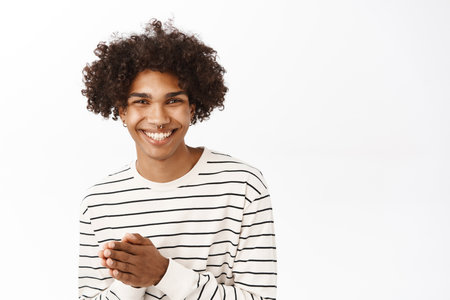 Close up portrait of smiling young man holding hands together, namaste, thank you gesture, appreciate smth, standing over white backgroundの写真素材