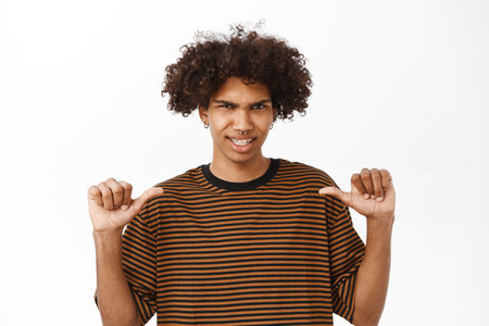 Confident guy pointing at himself and looks proud, self-promoting, feeling high self-esteem, stands over white studio backgroundの写真素材
