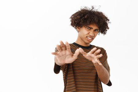 Portrait of guy showing stop, refusal gesture, rejecting smth with dislike face expression, standing over white backgroundの写真素材