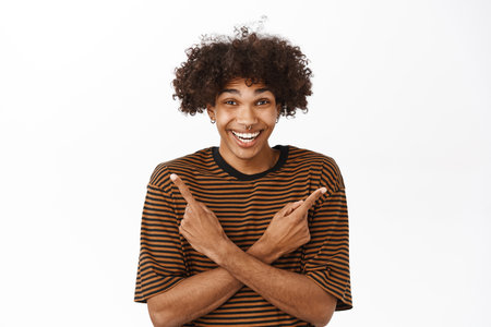 Happy laughing guy pointing sideways, showing left and right side, product banners with choices, standing over white backgroundの写真素材
