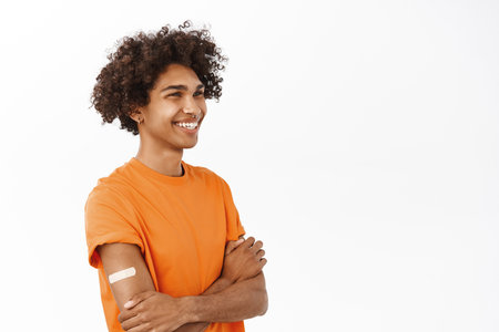 Portrait of smiling queer guy with vaccine shot, patch on arm from vaccination, covid-19 pandemic concept, standing over white backgroundの写真素材