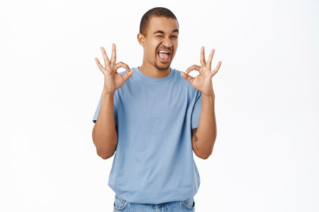 Nice, not bad. Smiling arab man shows okay, ok sign, recommends smth awesome, stands over white backgroundの写真素材