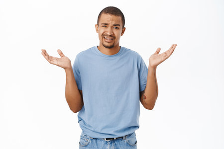 Portrait of arab guy looks confused, shrugs with hands sideways, stands over white backgroundの写真素材