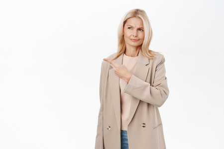 Disappointed middle aged woman, mature lady looks with upset, skeptical face, standing over white backgroundの写真素材