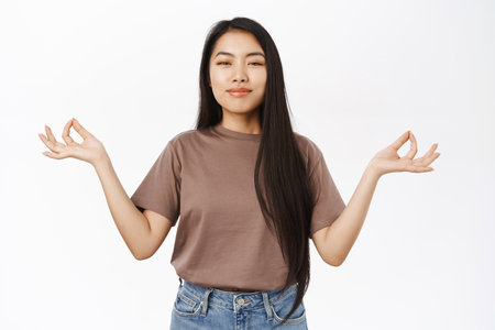 Asian woman meditating, practice yoga, breathe with relaxed, resting face, standing over white backgroundの写真素材