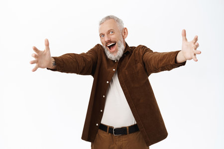 Smiling happy old man, grandfather stretching out hands, reaching for hug greeting, standing over white backgroundの写真素材