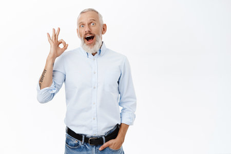 Image of businessman showing okay sign, ok gesture, approve, recommend something awesome, standing against white backgroundの写真素材