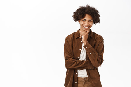 Young handsome man looking pleased, listening smth interesting, good idea, standing over white backgroundの写真素材