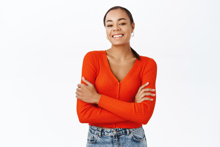 People. Smiling african american girl standing in confident, power pose, arms crossed on chest, white backgroundの写真素材