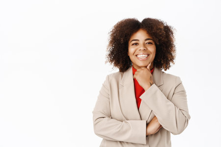 Young smiling black woman in suit, businesswoman looking professional, standing over white backgroundの写真素材