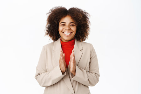 Good job, well done. Smiling african american businesswoman clap hands, applausing you and praising, standing over white backgroundの写真素材