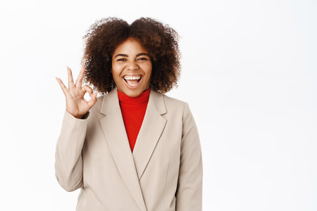 Corporate people. Happy african american businesswoman praise smth excellent, gives compliment, positive feedback, stands over white backgroundの写真素材