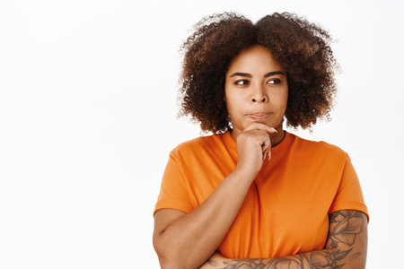 African american girl thinking, looking thoughtful and serious, stands over white backgroundの写真素材