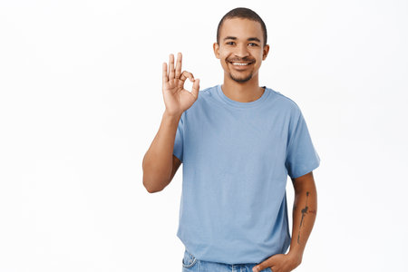 Excellent. Smiling arab man shows okay, ok sign in approval, agree with you, recommending, stands over white backgroundの写真素材