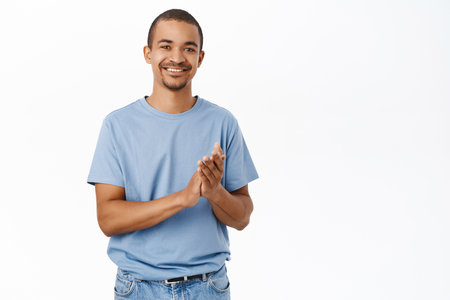 Happy smiling man applausing, clap hands to praise you, standing over white backgroundの写真素材