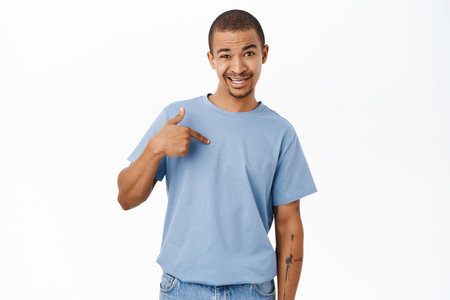 Portrait of arab guy pointing at himself with confused face, who me gesture, looking puzzled, standing over white backgroundの写真素材