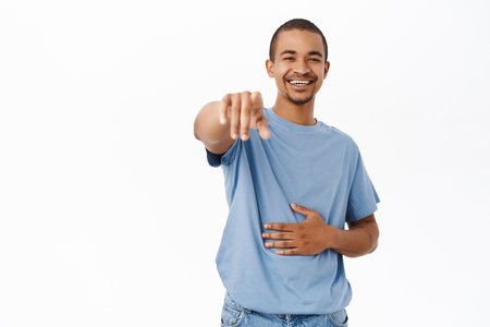 Haha funny. Laughing and smiling man points finger at camera, see smth hilarious, stands over white backgroundの写真素材