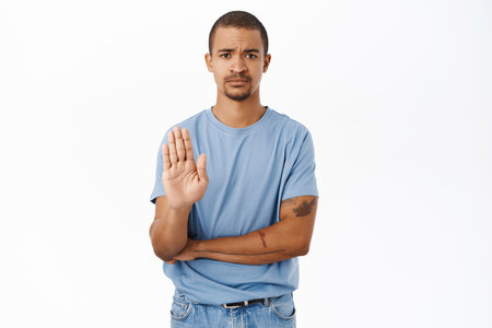 Please stop. Concerned man shows palm taboo gesture, refusing, rejecting and prohibiting smth, standing over white backgroundの写真素材