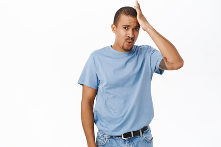 Worried arab guy, touch head, forgot or remember smth, standing nervous over white backgroundの写真素材