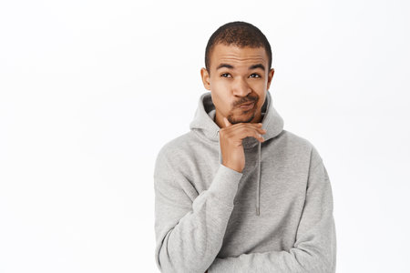 Portrait of european man thinking, looking thoughtful up, having an idea, standing over white background, making choiceの写真素材